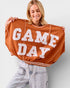 Person holding up a brown 'GAME DAY' sweatshirt against a plain background