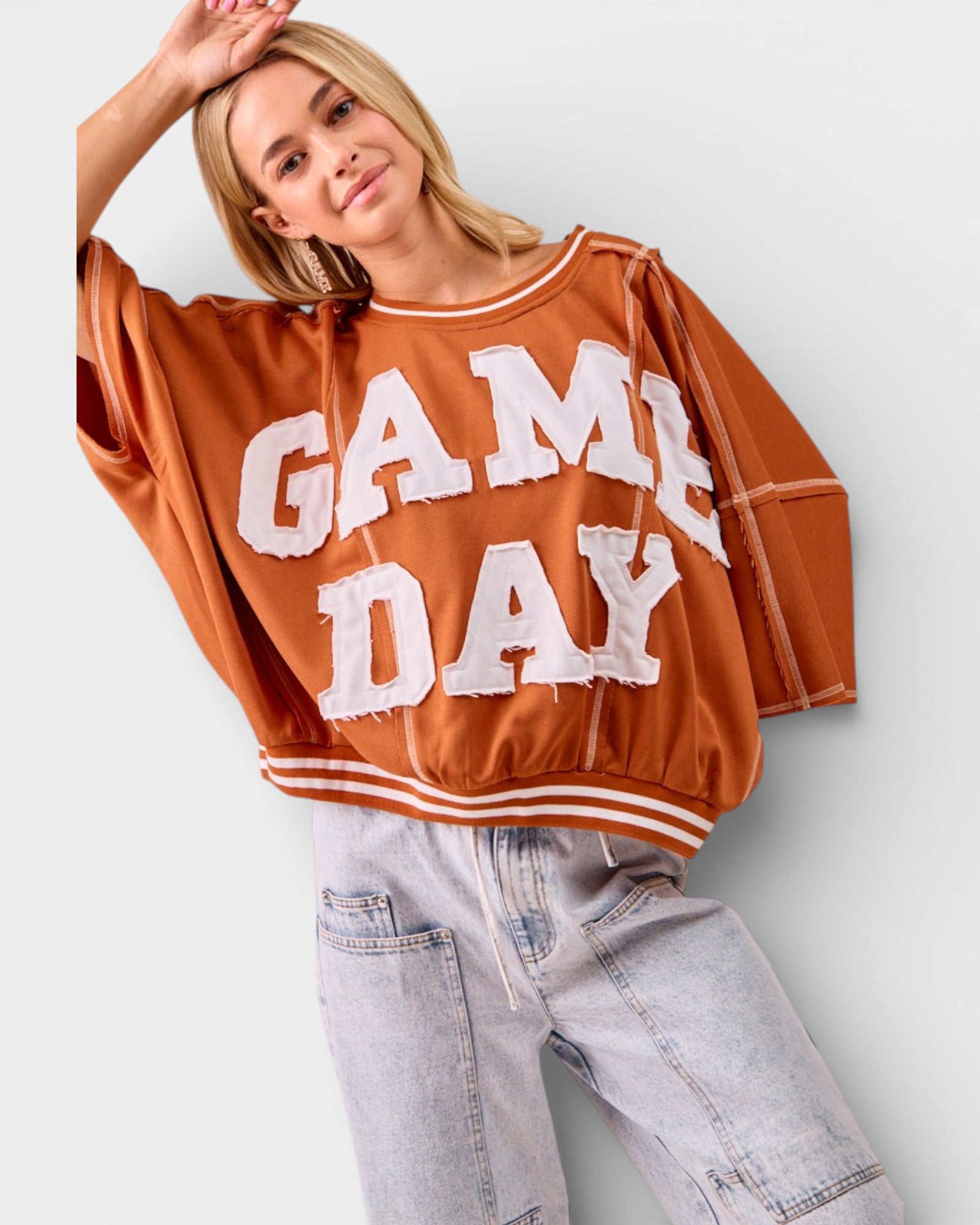 Person wearing a brown 'GAME DAY' sweatshirt against a white background