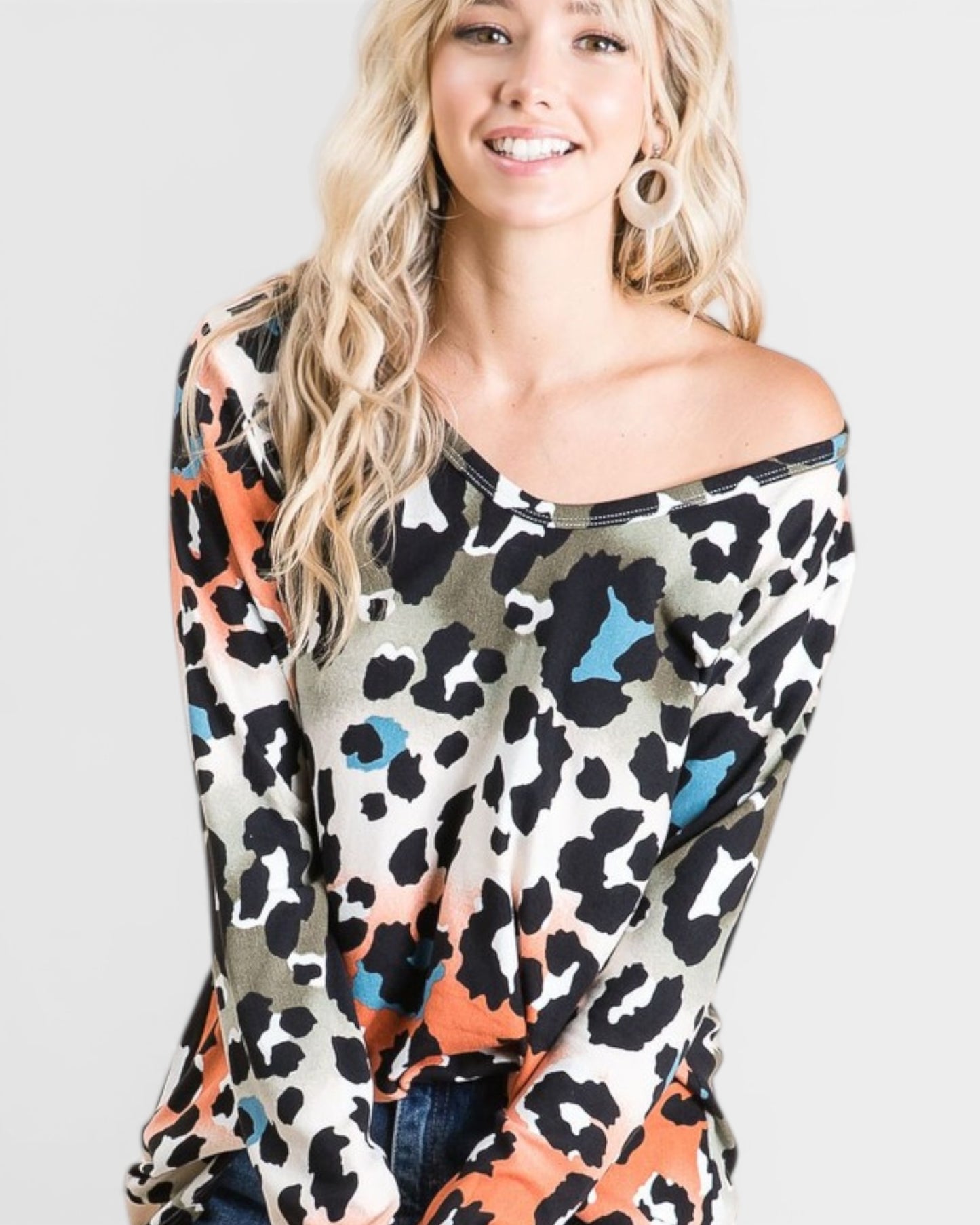 Woman wearing a colorful leopard print top against a plain background