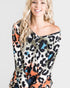 Woman wearing a colorful leopard print top against a plain background