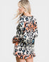 Woman wearing a leopard print dress with colorful patterns on a white background