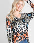 Woman wearing a colorful leopard print top with blue accents on a plain background