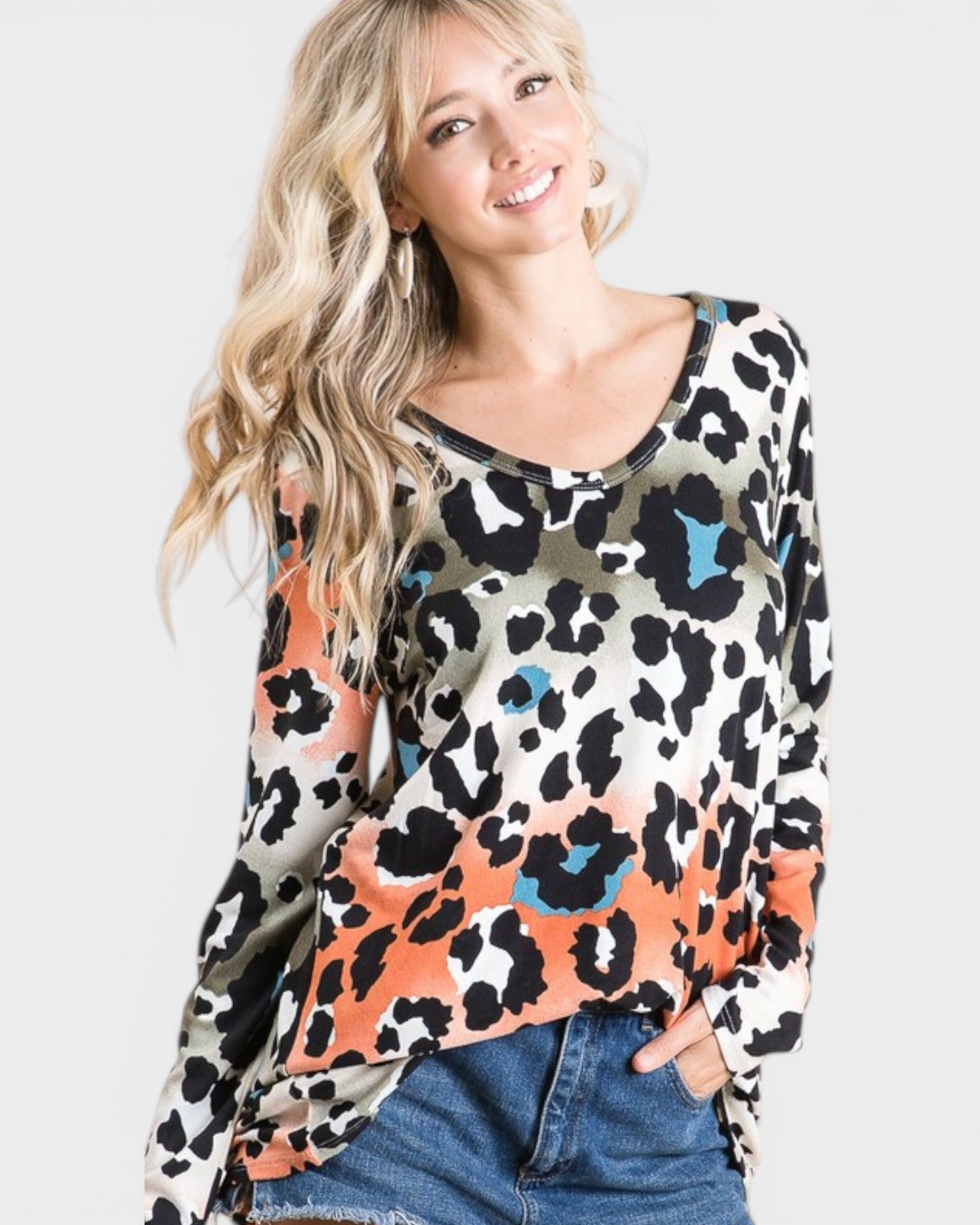 Woman wearing a colorful leopard print top with a plain background