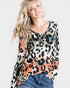 Woman wearing a colorful leopard print top with a plain background