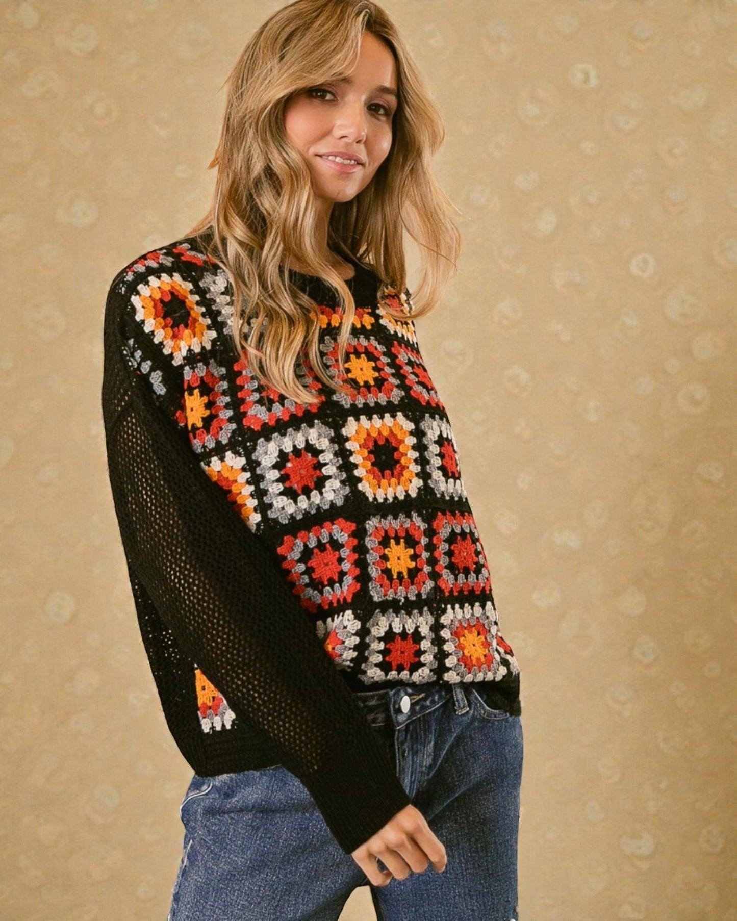 Woman wearing a colorful crochet sweater against a beige background