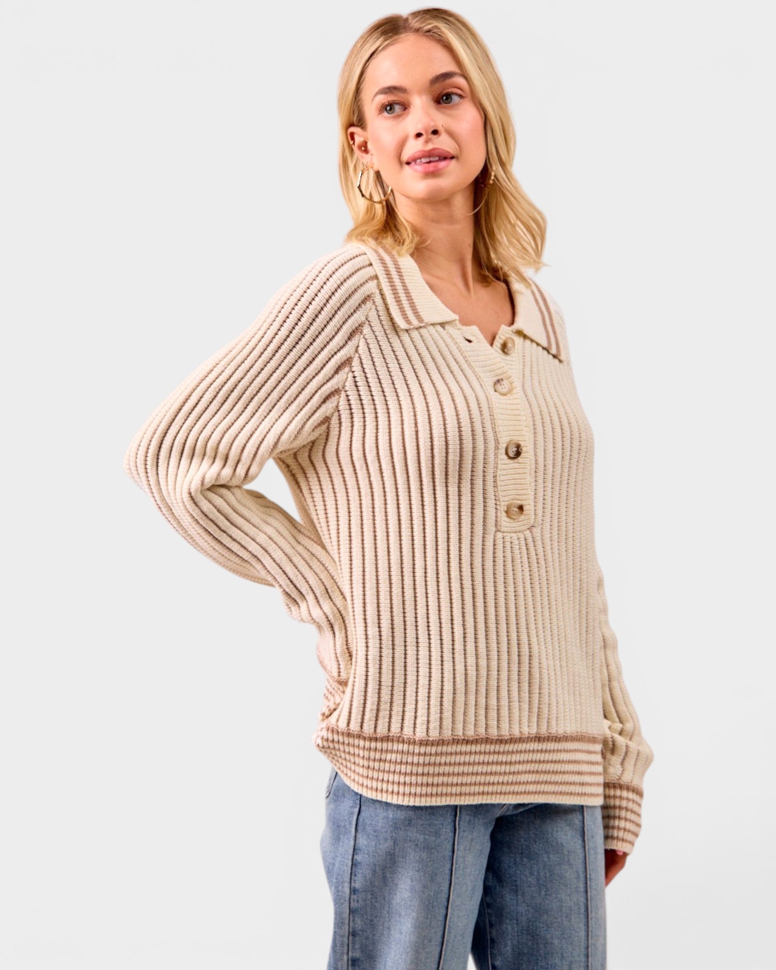 Woman wearing a beige ribbed sweater with buttons on a light gray background