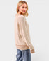 Woman wearing a beige ribbed sweater and blue jeans on a white background