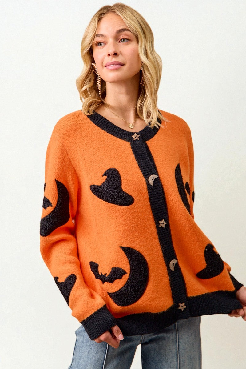 Woman wearing an orange Halloween-themed cardigan with black graphics on a white background