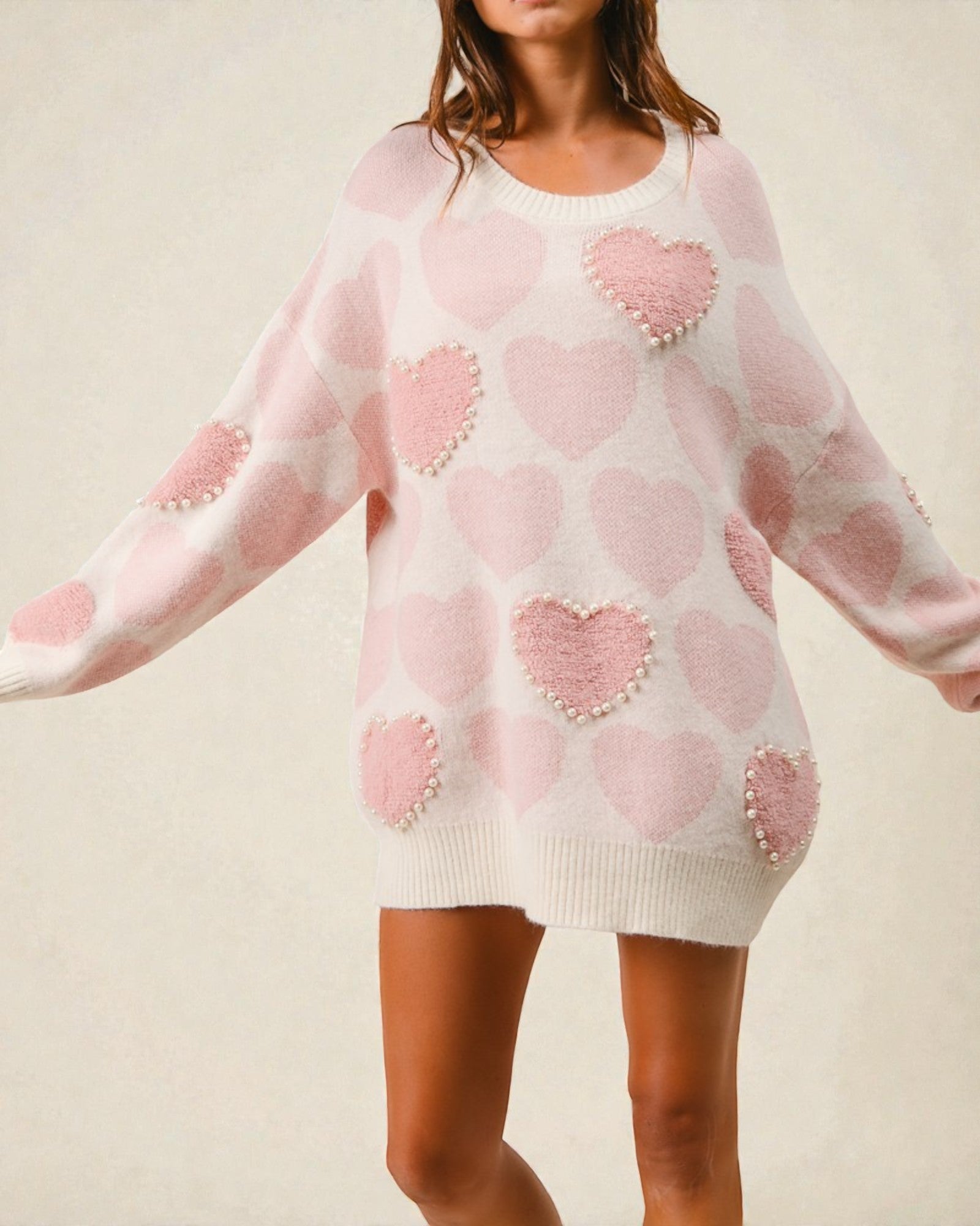 Pink sweater dress with heart patterns on a neutral background