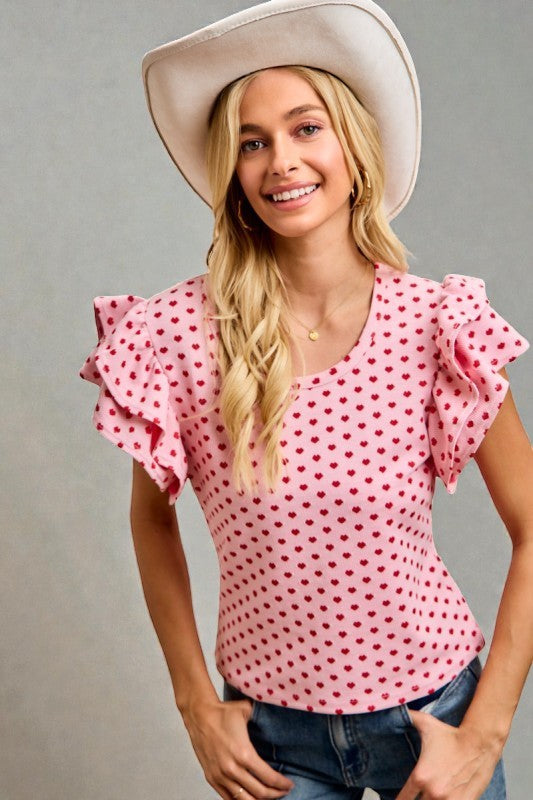 Woman wearing a pink polka dot blouse and white cowboy hat against a gray background