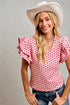 Woman wearing a pink polka dot blouse and white cowboy hat against a gray background
