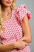Woman wearing a pink top with red patterns against a gray background