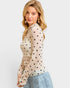 Woman wearing a beige blouse with black polka dots and light blue jeans on a white background
