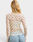 Woman wearing a beige long-sleeve top with black polka dots on a plain background