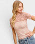 Woman wearing a pink lace top and jeans on a white background