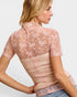 Woman wearing a pink lace top with a white background
