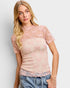 Woman wearing a pink lace top with a plain background