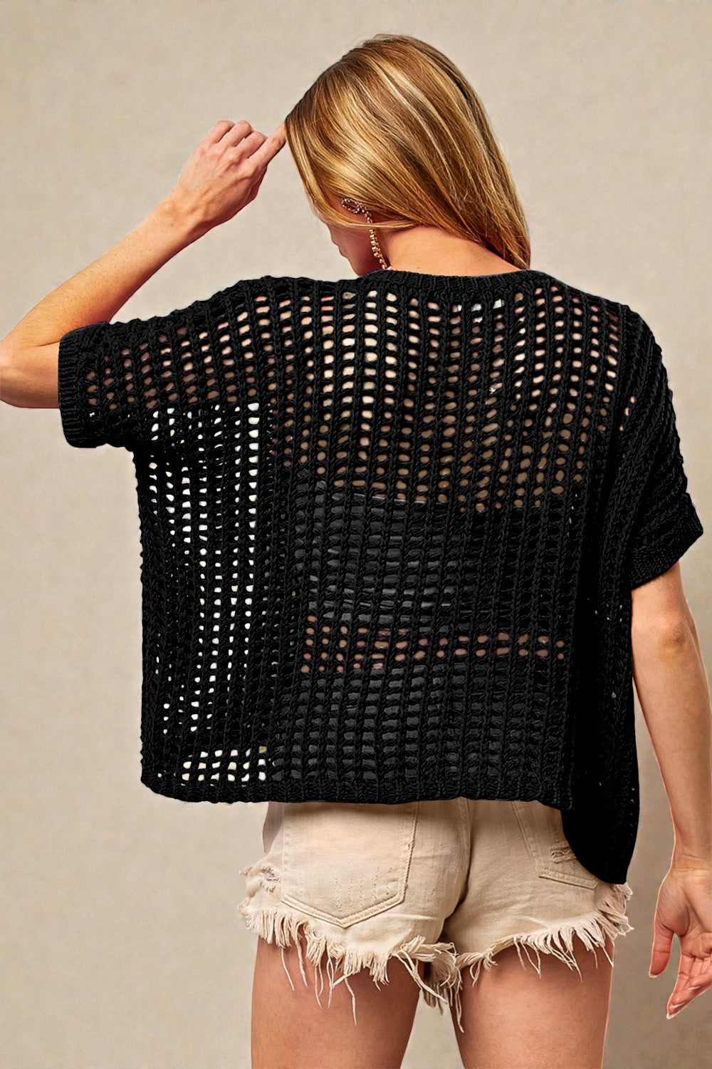 Person wearing a black crochet top and white shorts against a neutral background