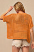 Woman wearing an orange crochet top against a beige background