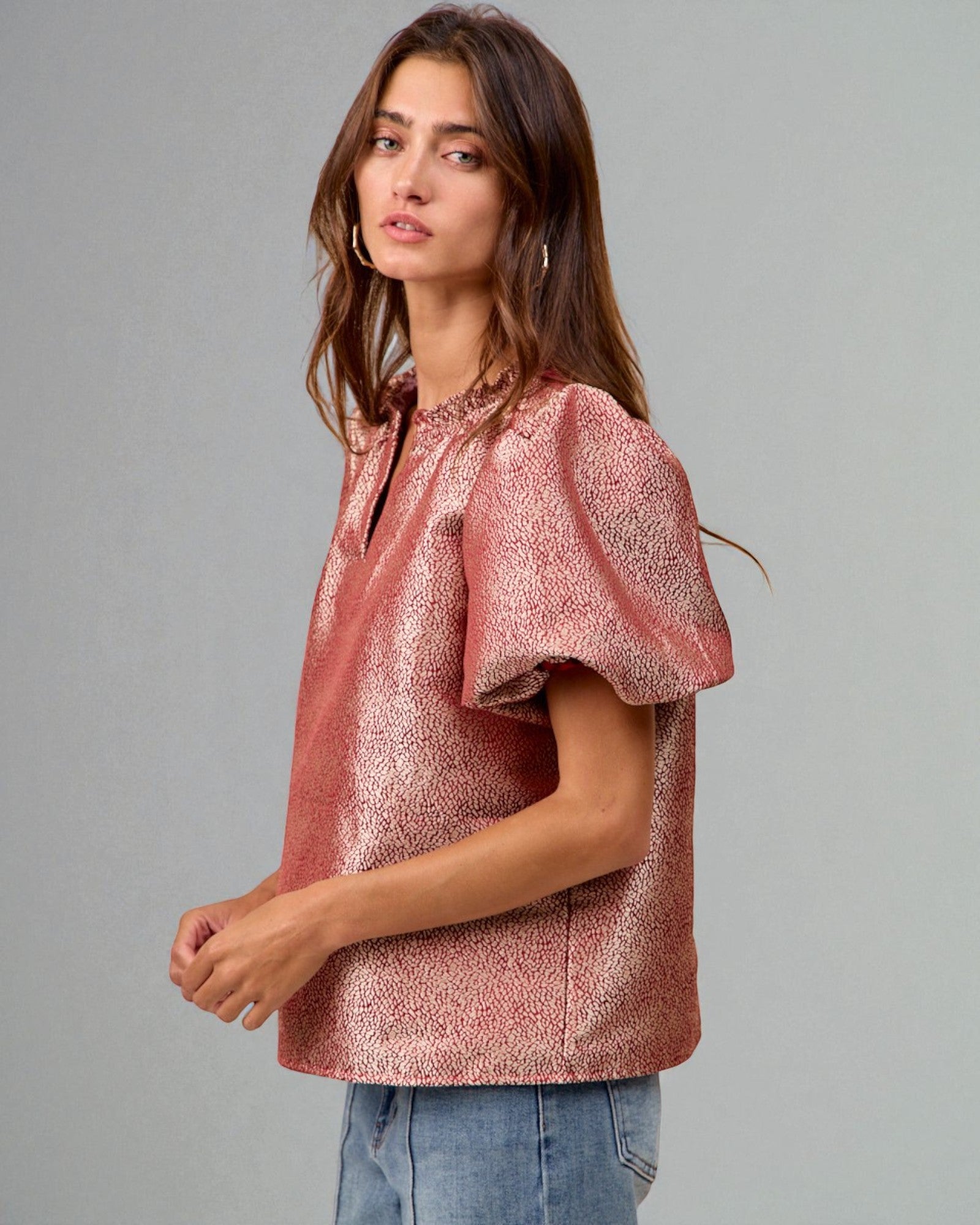 Woman wearing a pink metallic blouse against a gray background