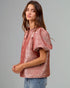 Woman wearing a pink metallic blouse against a gray background