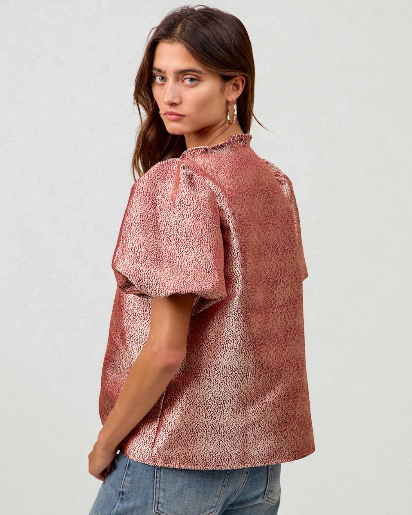 Woman wearing a pink textured blouse against a white background