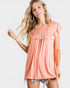 Woman wearing a peach-colored top with ruffled sleeves on a white background