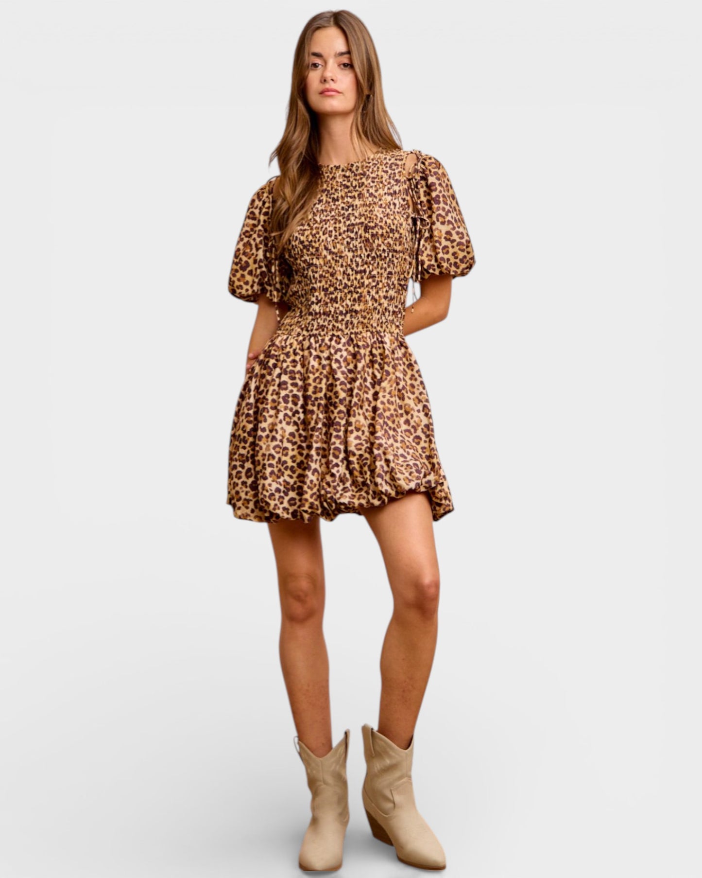 Woman wearing a leopard print dress with beige boots on a white background