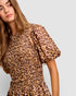 Woman wearing a leopard print dress against a plain background