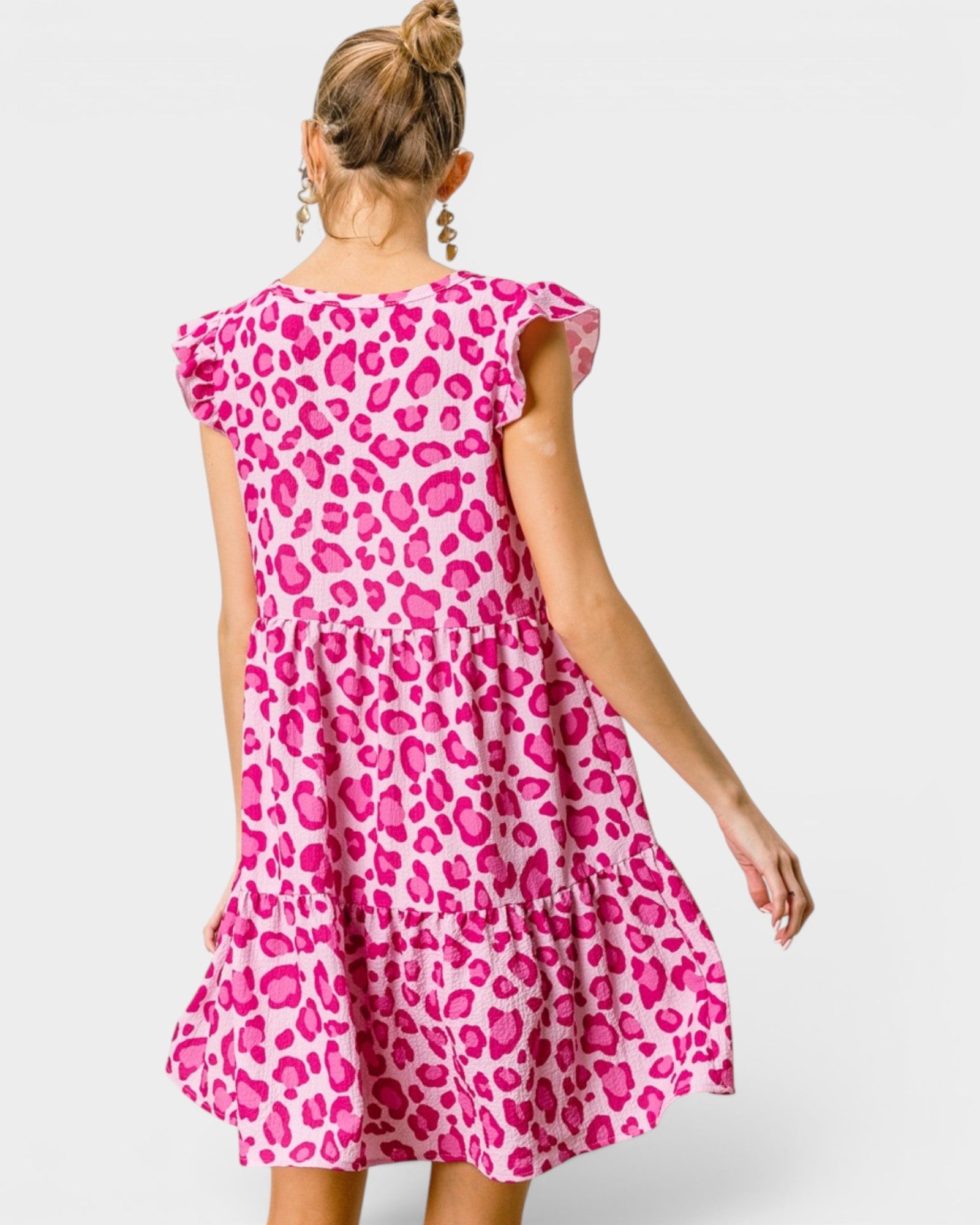Woman wearing a pink leopard print dress on a white background