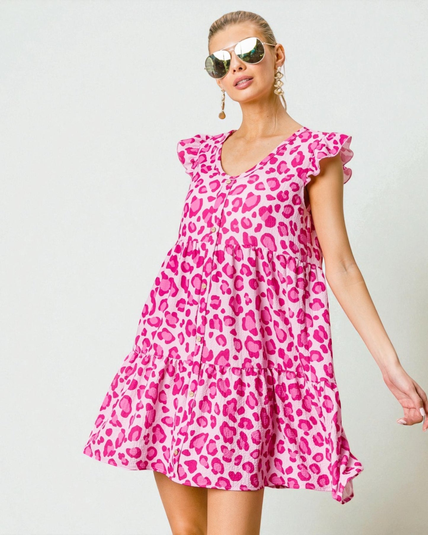 Woman wearing a pink leopard print dress against a light background