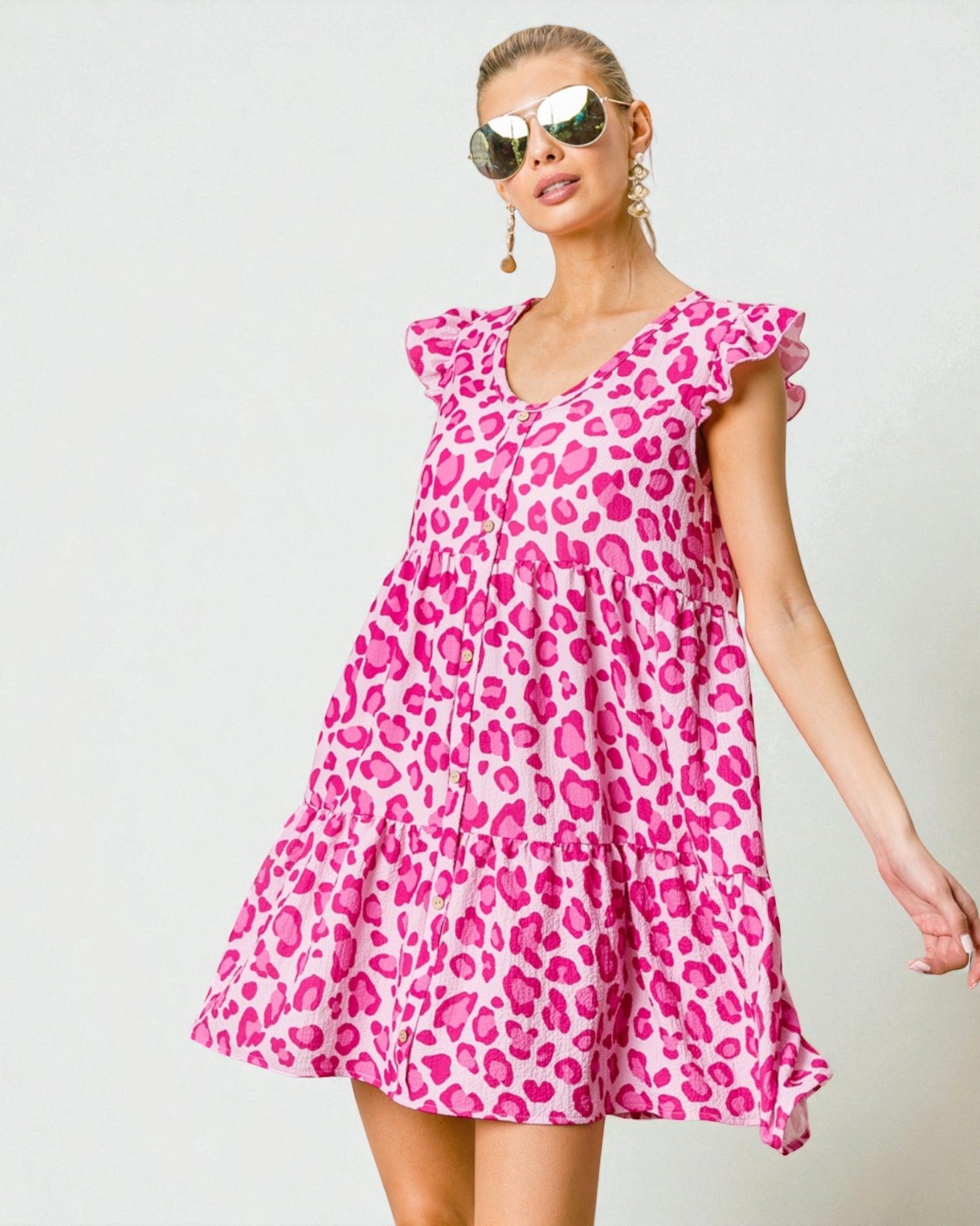 Woman wearing a pink leopard print dress against a light background