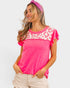 Woman wearing a bright pink top with a patterned headband on a white background