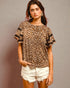 Woman wearing a leopard print top with black lace sleeves against a gray background