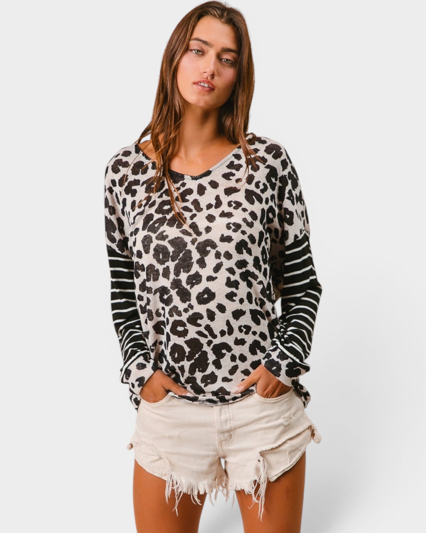 Woman wearing a leopard print long-sleeve top and white shorts on a plain background
