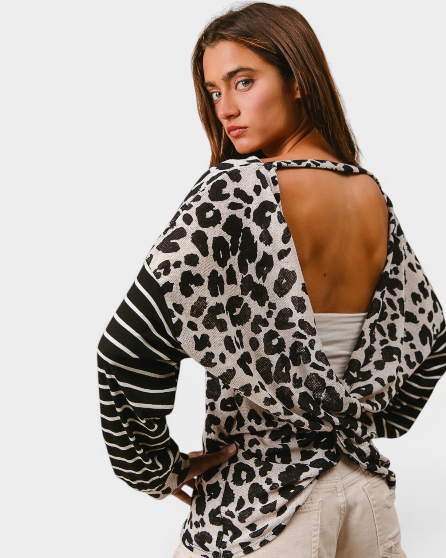Woman wearing a leopard print top with open back on a plain background