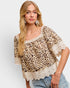 Woman wearing a leopard print top with lace details on a plain background