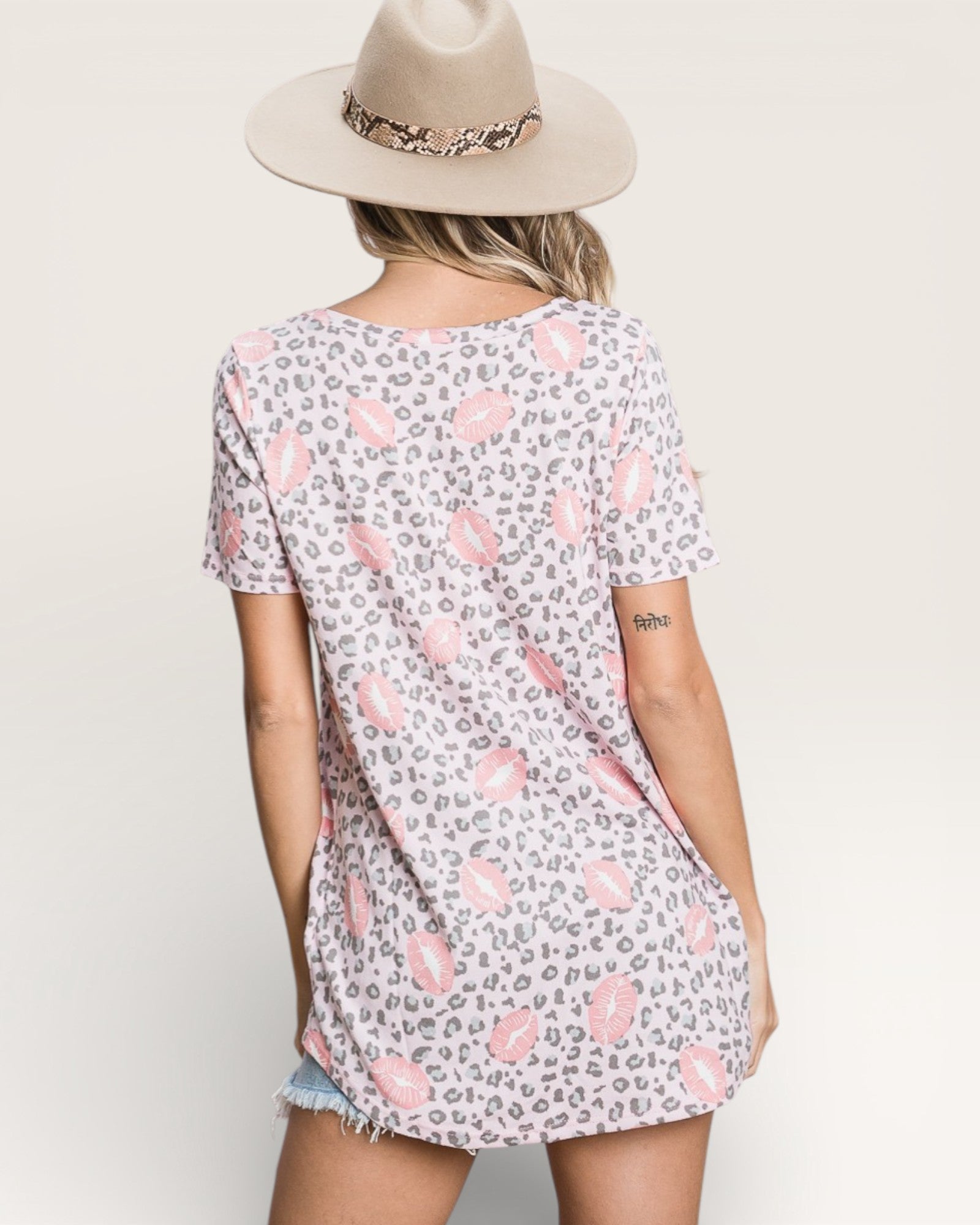 Person wearing a patterned t-shirt and hat on a plain background