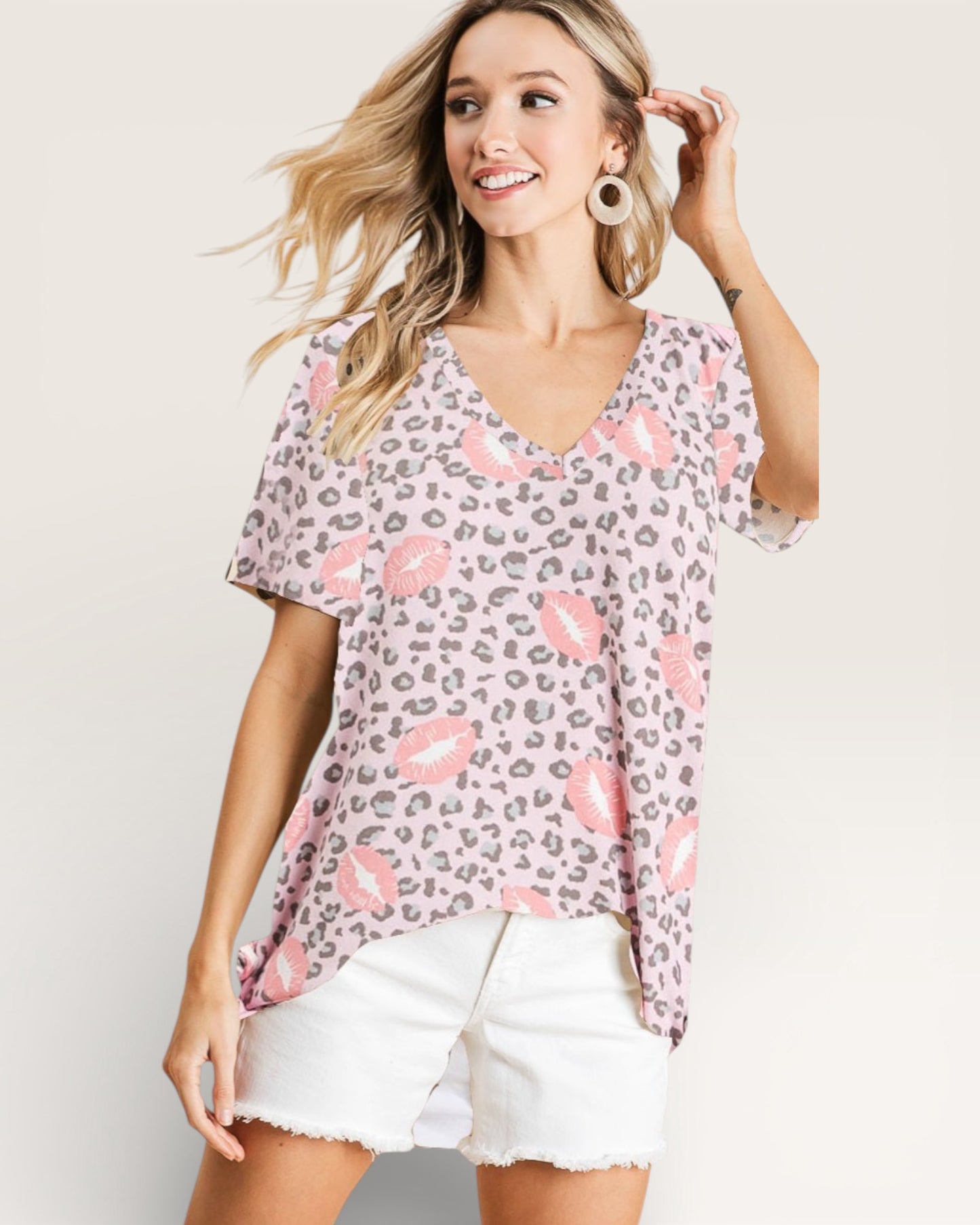 Woman wearing a patterned top with pink accents on a plain background