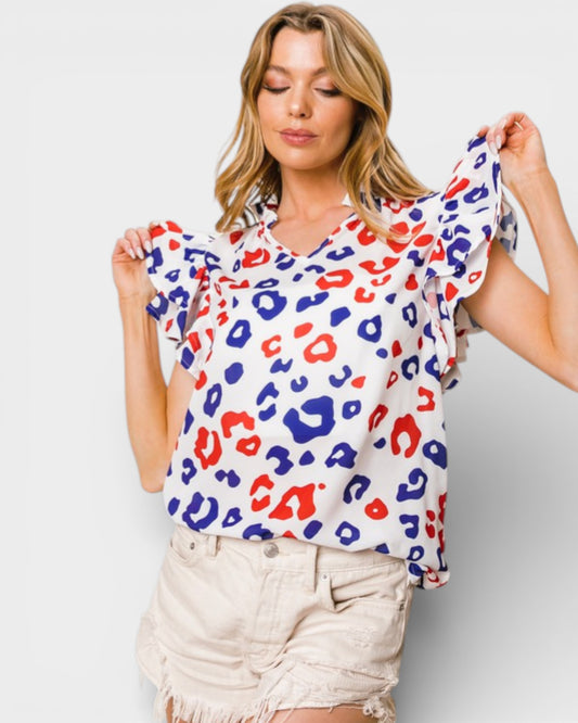 Woman wearing a colorful leopard print top against a plain background