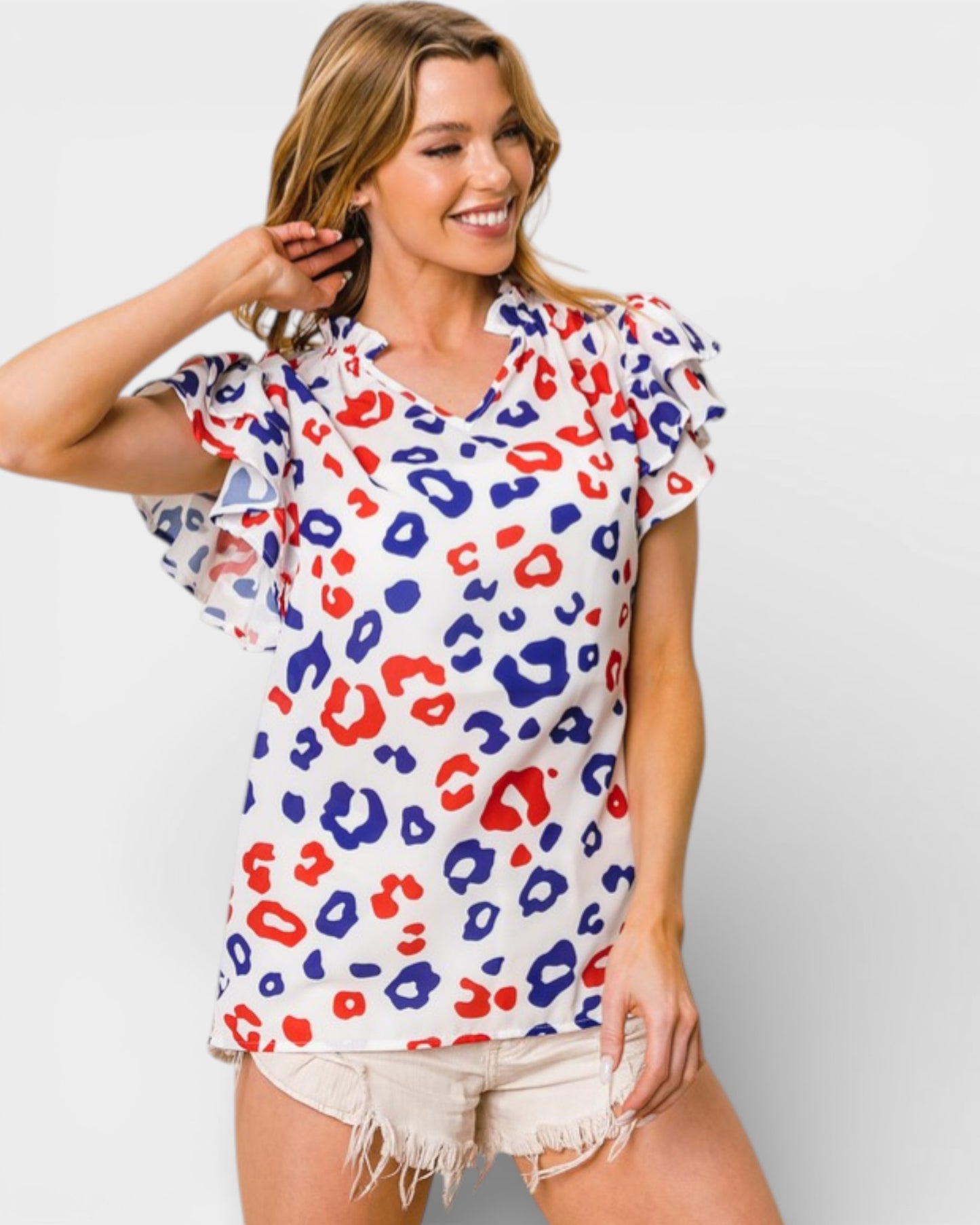 Woman wearing a colorful leopard print top against a plain background