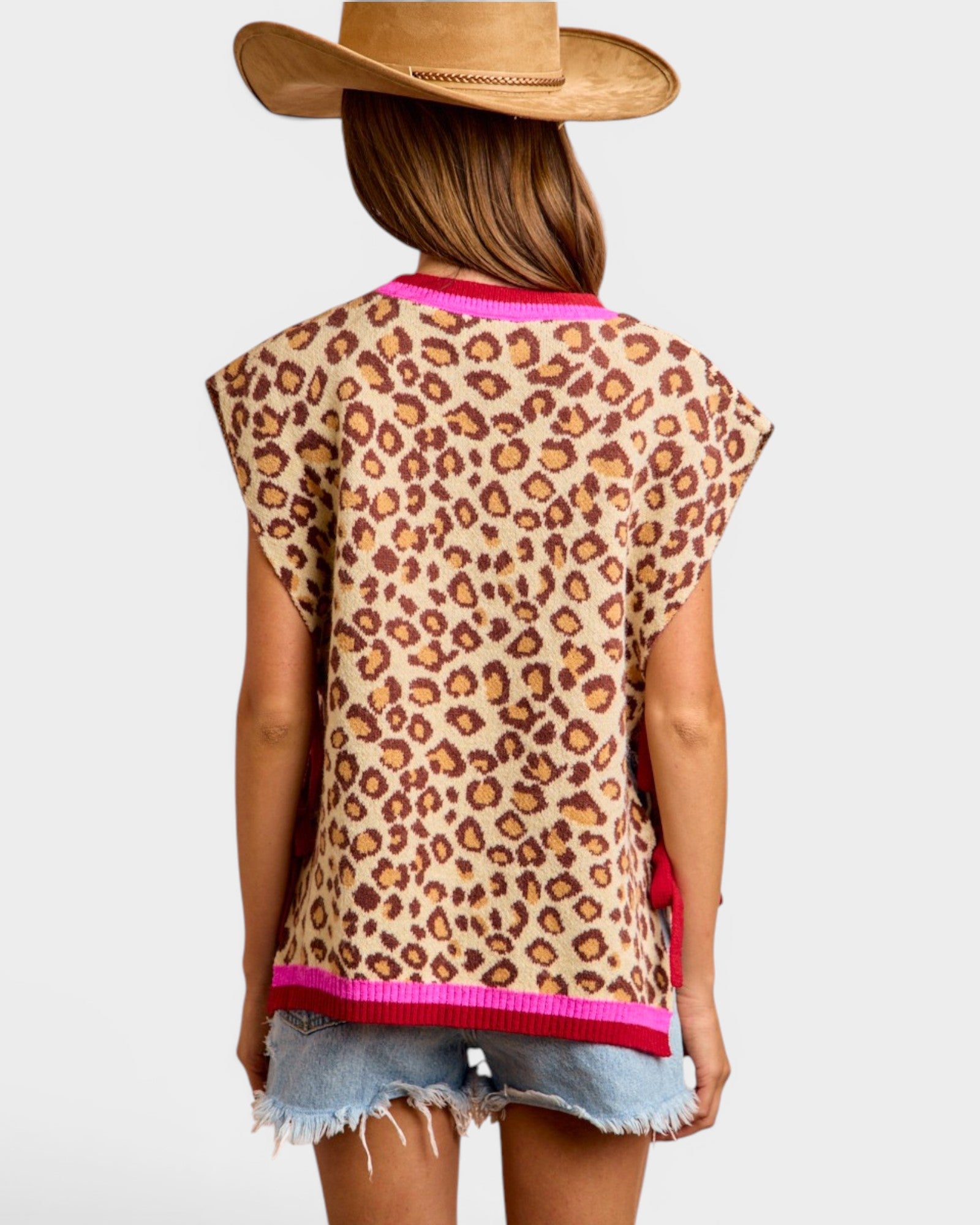 Person wearing a leopard print top with pink trim and denim shorts on a white background