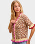 Woman wearing a leopard print cardigan with pink trim on a plain background