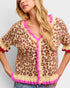 Woman wearing a leopard print cardigan with pink trim on a light gray background