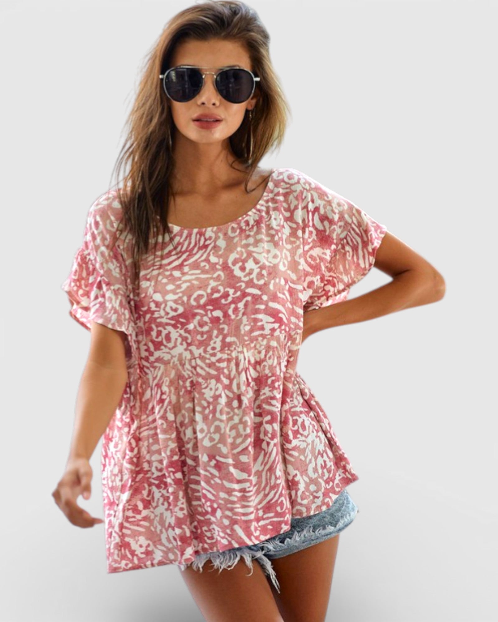 Woman wearing a pink floral blouse and denim shorts on a white background