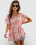 Woman wearing a pink floral blouse and denim shorts on a white background