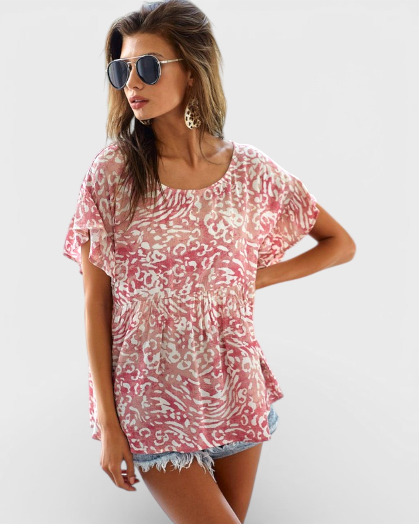 Woman wearing a pink patterned top and denim shorts on a white background