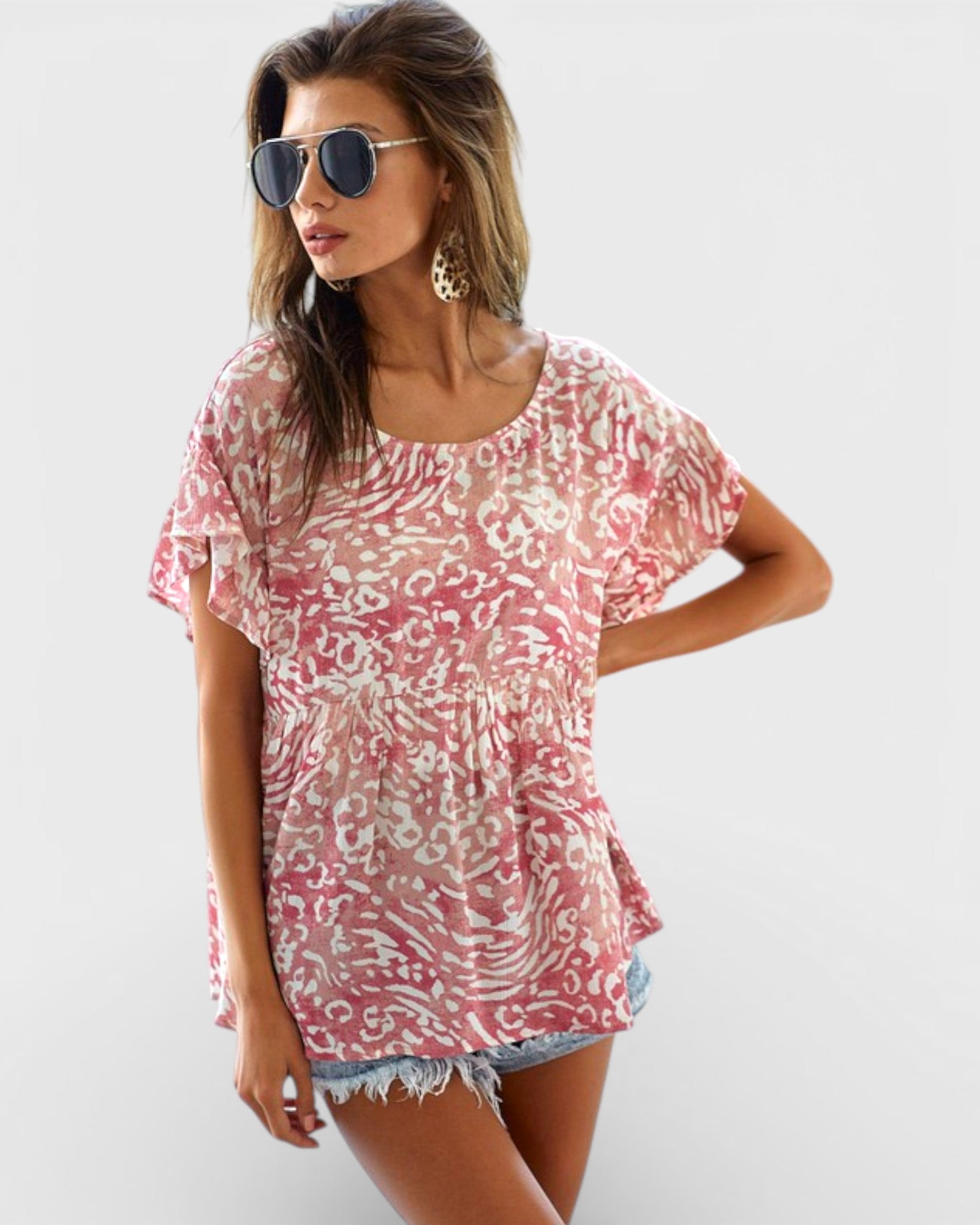 Woman wearing a pink patterned top and denim shorts on a white background