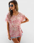 Woman wearing a pink patterned top and denim shorts on a white background
