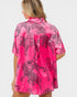 Woman wearing a pink satin shirt with black leopard print patterns on a white background